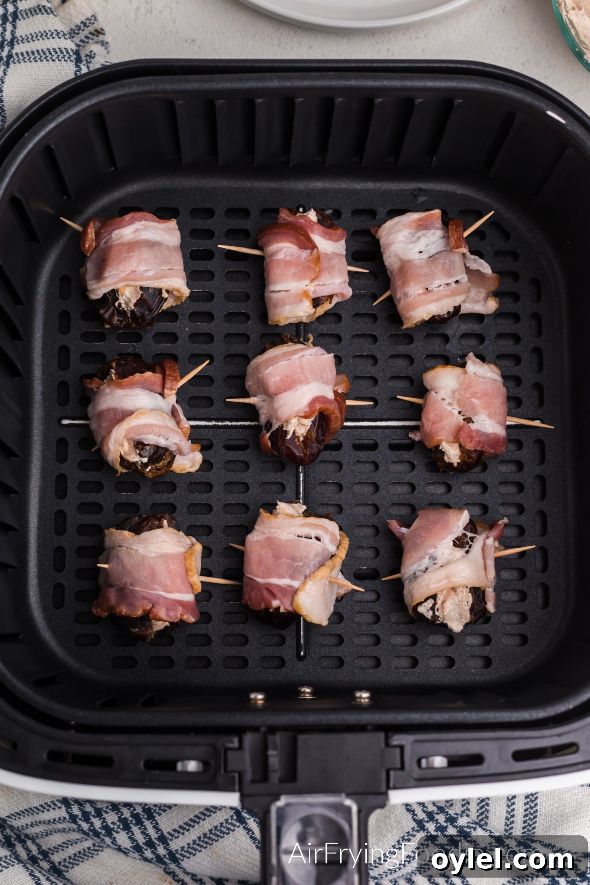 Air Fryer Bacon-Wrapped Dates Recipe 8 Bacon wrapped dates in the basket of the air fryer.