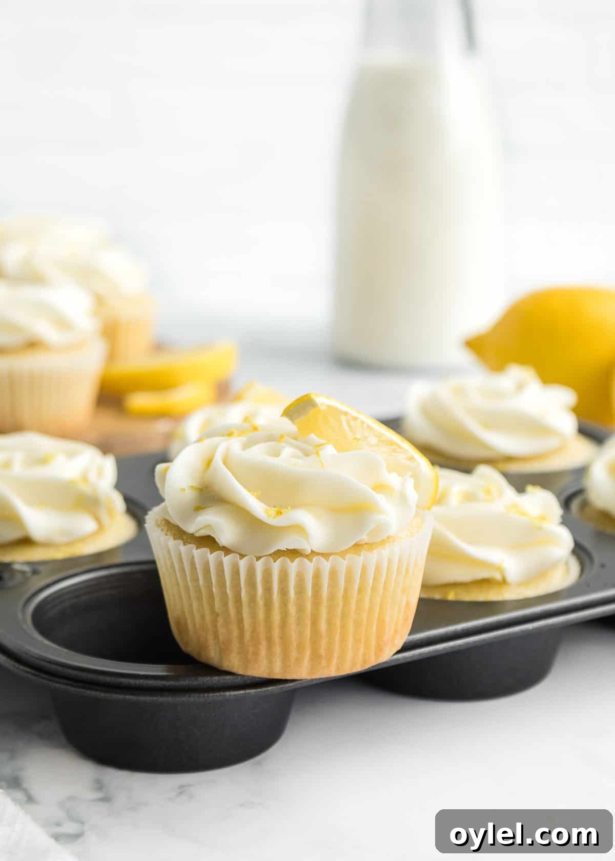 Irresistible Lemon Dessert Recipes 2 One lemon cupcake with lemon slice garnish placed on top of the muffin tin.