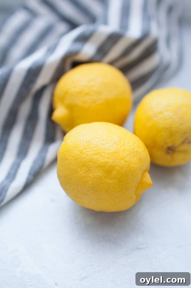 Irresistible Lemon Dessert Recipes 3 Lemons next to striped linen napkin.