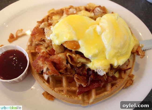 white plate with chicken and waffles with poached eggs at Floyd's Diner in Victoria British Columbia, Canada.