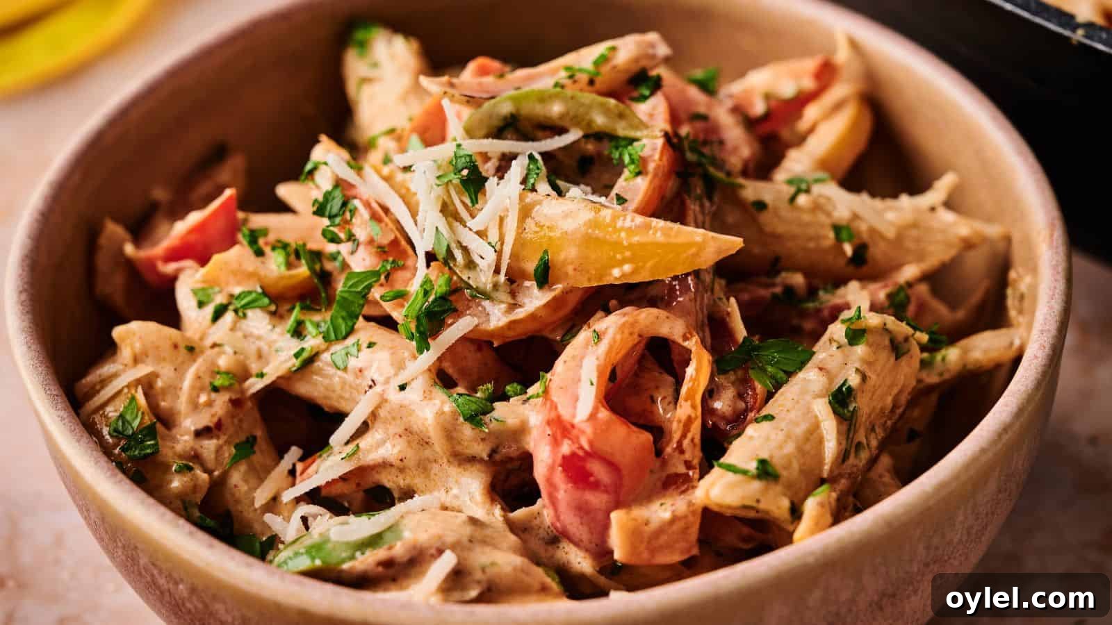 35 Chicken Breast Recipes to Simplify Weeknight Dinners 11 A bowl of penne pasta with creamy sauce, sliced bell peppers, and fresh parsley, topped with grated cheese.