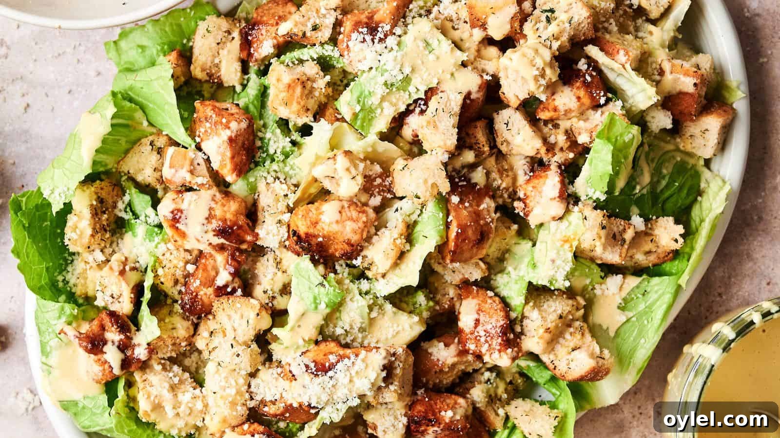 35 Chicken Breast Recipes to Simplify Weeknight Dinners 21 A Caesar salad topped with grilled chicken pieces, croutons, and grated cheese on a bed of romaine lettuce. Dressing is served on the side.