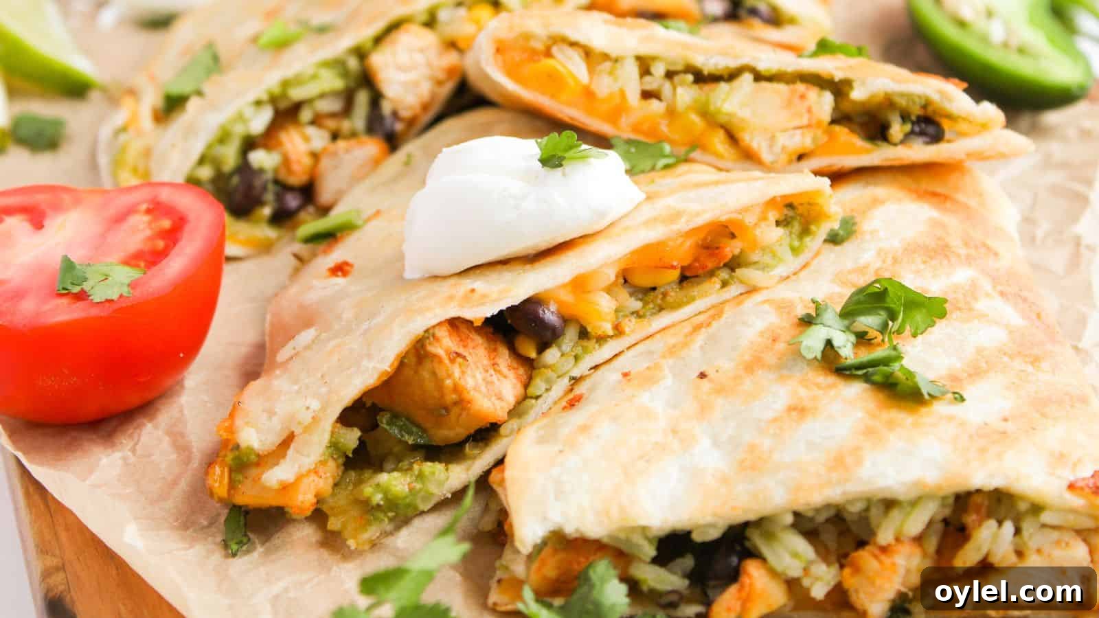 35 Chicken Breast Recipes to Simplify Weeknight Dinners 3 Quesadillas filled with rice, beans, and chicken, topped with sour cream and cilantro. Sliced tomato and jalapeño are on the side.