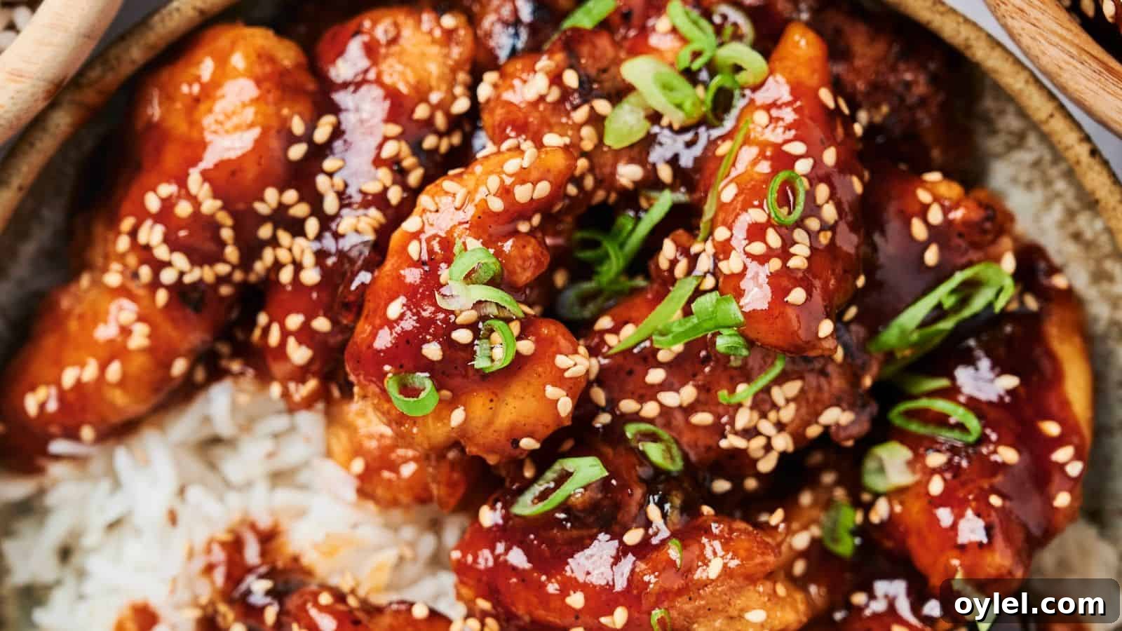 35 Chicken Breast Recipes to Simplify Weeknight Dinners 32 A close-up of glazed chicken pieces with sesame seeds and chopped scallions on a bed of rice.