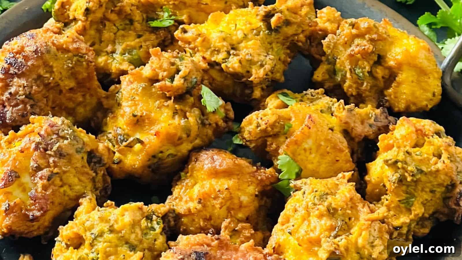 35 Chicken Breast Recipes to Simplify Weeknight Dinners 34 Close-up of a plate filled with golden-brown pakoras, showing their crispy and textured surface, garnished with pieces of cilantro.