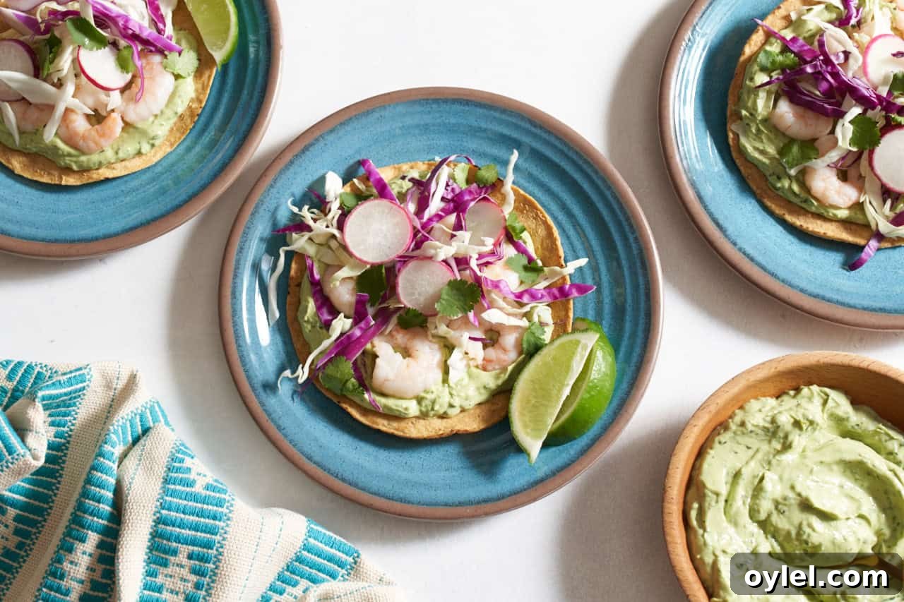 Crispy Mexican Shrimp Tostadas with Avocado Crema 2 Shrimp tostadas with avocado crema on blue plates topped with cabbage, radishes and cilantro, a bowl of avocado crema is in the bottom right.