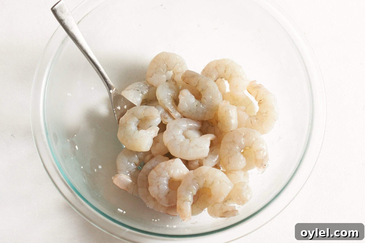 Crispy Mexican Shrimp Tostadas with Avocado Crema 4 Raw shrimp seasoned with kosher salt in a bowl with a fork.