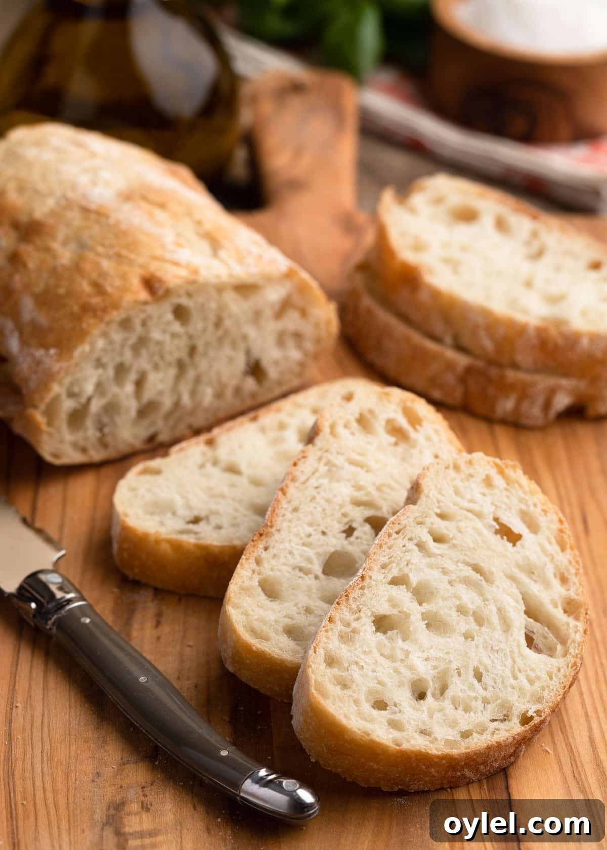sliced loaf of ciabatta bread on a wooden cutting board with a bread knife