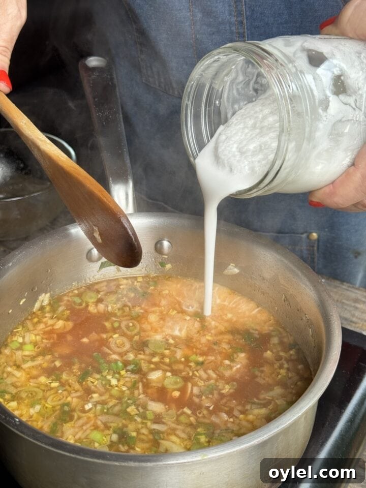 Coconut Curry Salmon in Creamy Fragrant Broth 8 a photo of pouring coconut milk into the broth mixture