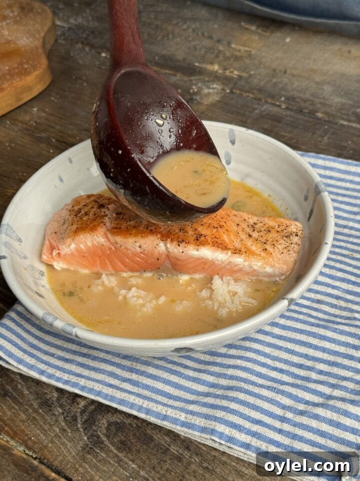 Coconut Curry Salmon in Creamy Fragrant Broth 10 a photo of salmon in a bowl with a ladle of broth over it