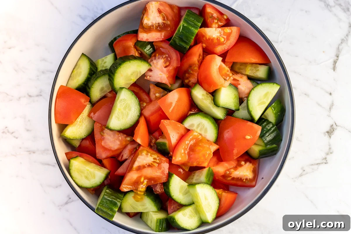 Chopped tomatoes and cucumber in a big bowl from above for making a Greek salad.