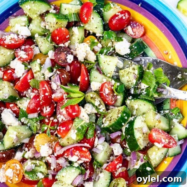 Closeup overhead of a colorful bowl of the salad, with salad servers in it.