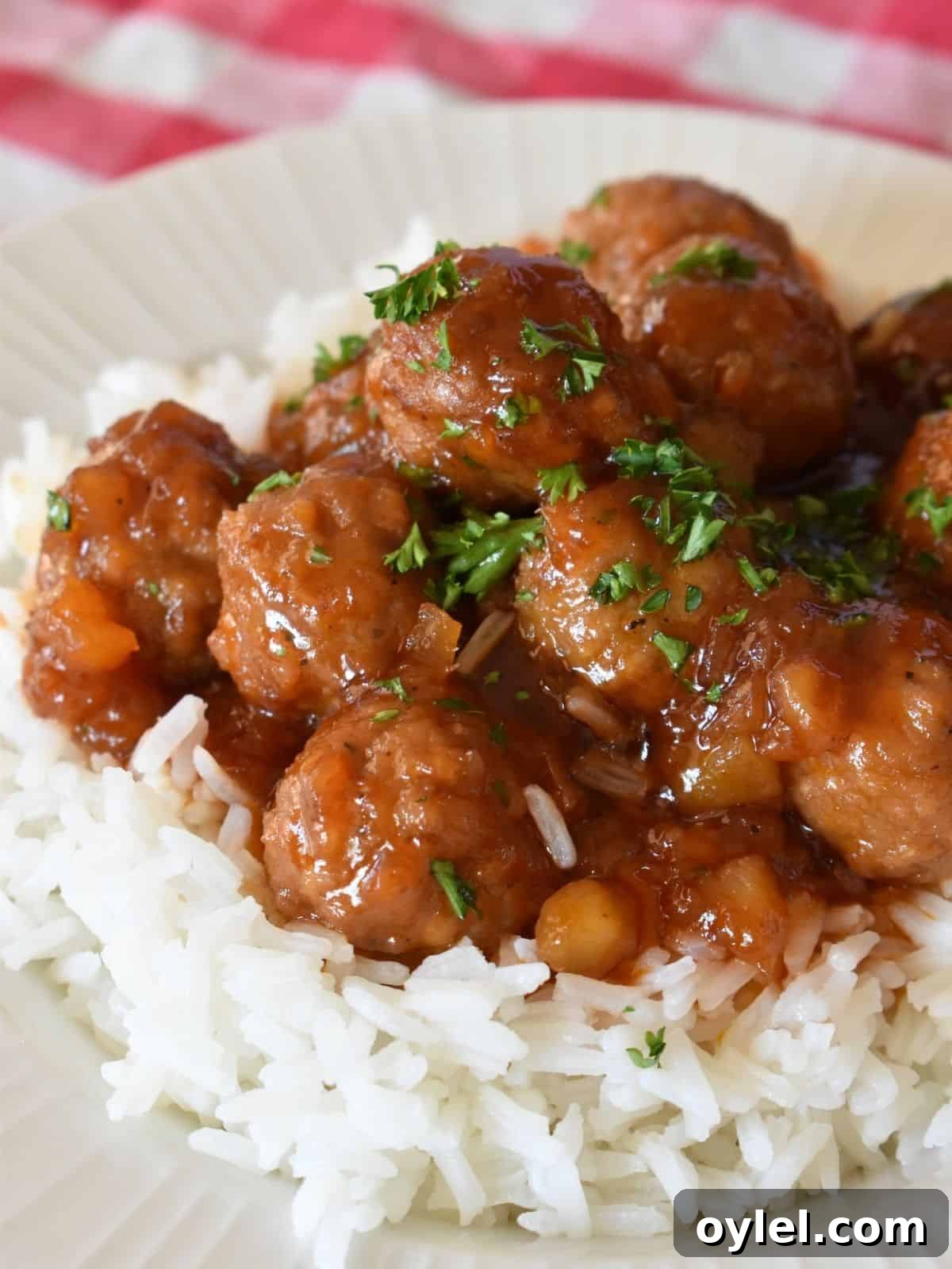 4-Ingredient Slow Cooker Hawaiian Meatballs 7 Slow cooker Hawaiian meatballs on white rice with parsley sprinkled on top.
