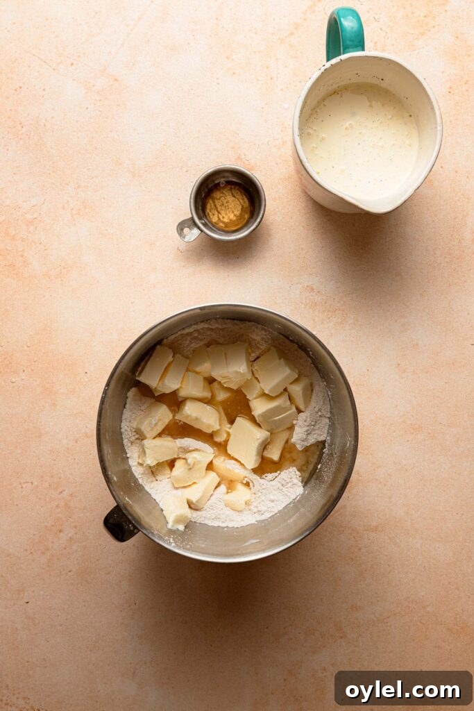A mixing bowl with flour and butter. A small bowl with apple cider vinegar. A large cup with heavy cream.