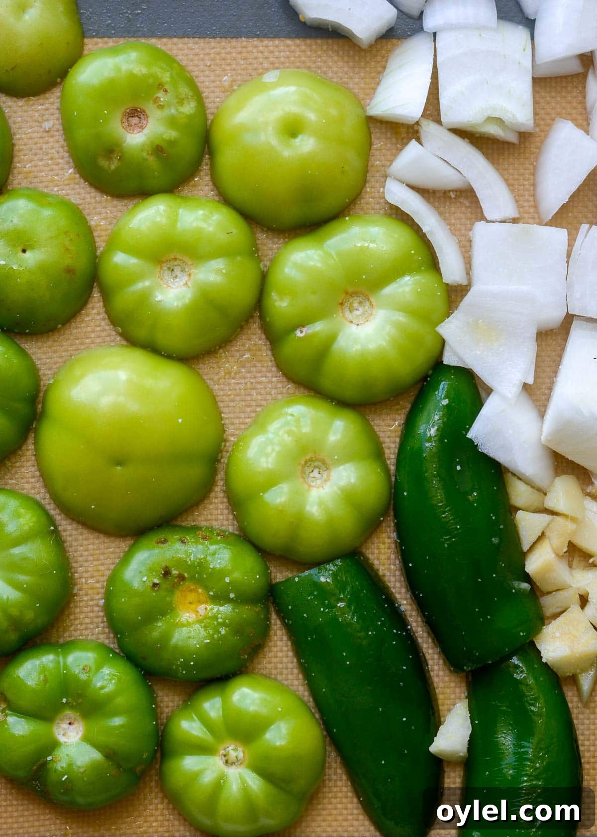 Authentic Roasted Tomatillo Salsa Recipe 5 tomatillos, jalapeno, and onion on a silicone lined sheet pan