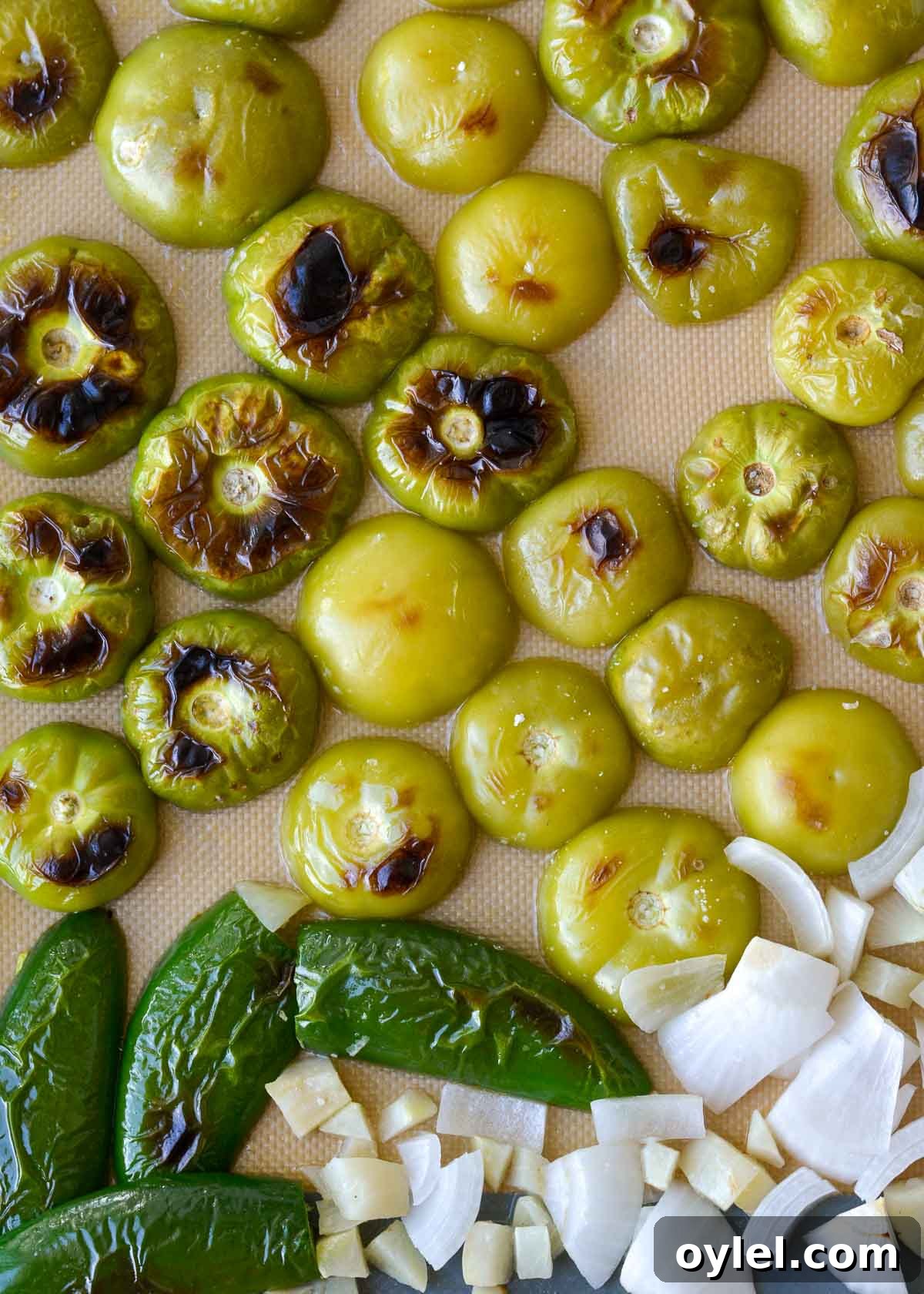 Authentic Roasted Tomatillo Salsa Recipe 6 roasted tomatillos, jalapeno, and onion on a sheet pan