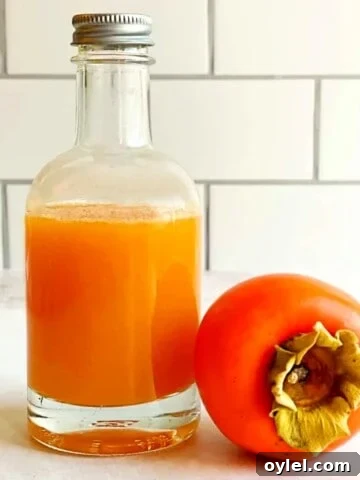 persimmon syrup in a bottle and a fresh persimmon fruit