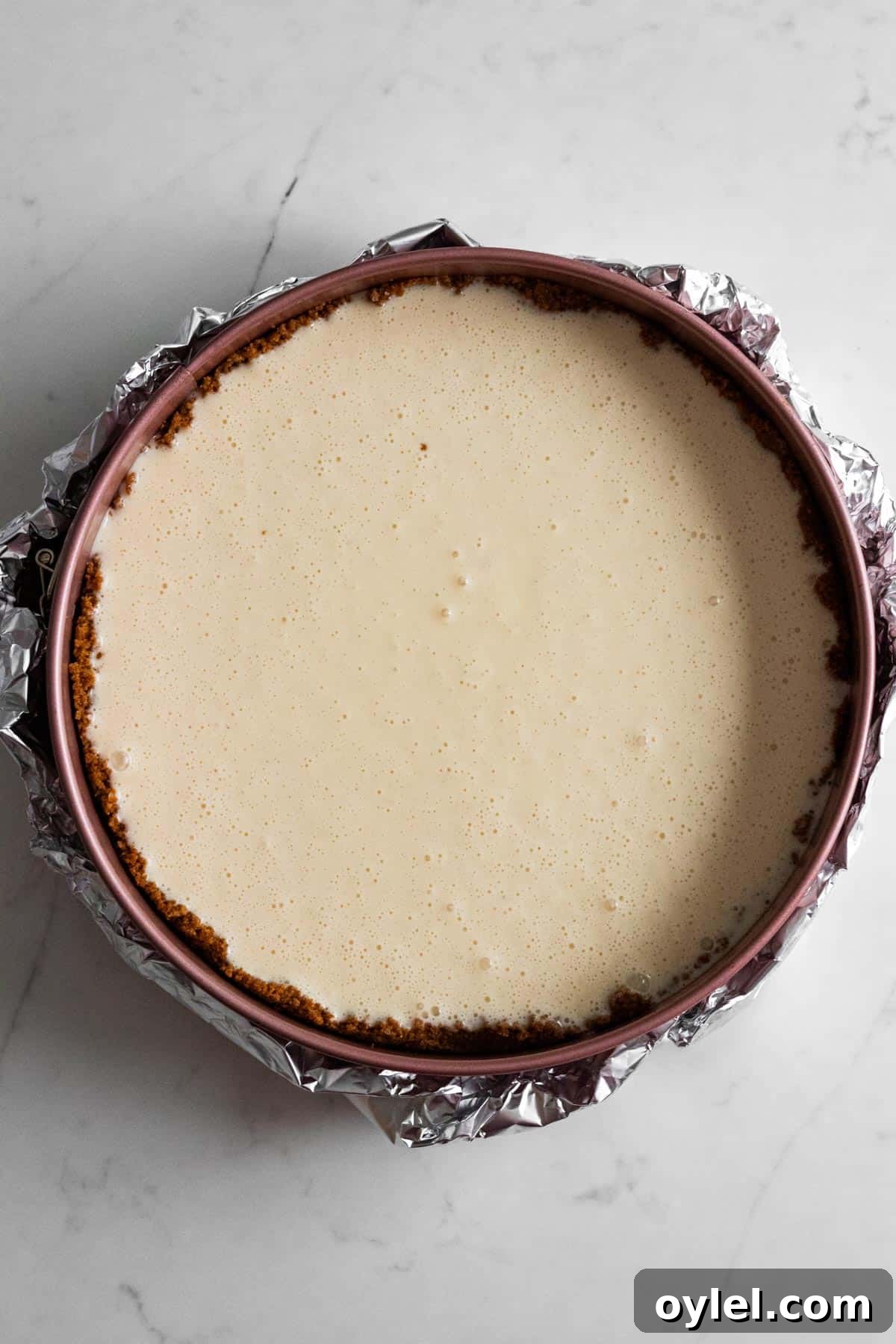 unbaked cheesecake batter in springform pan wrapped in foil