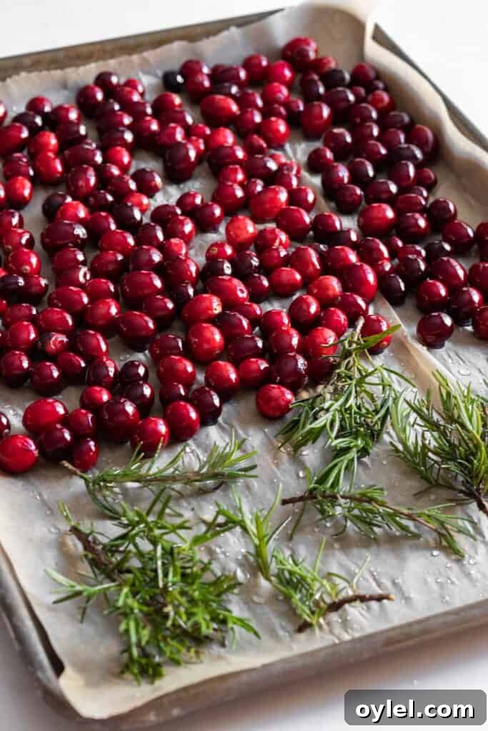 cranberries and rosemary on a parchment lined baking tray