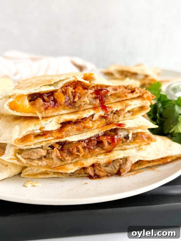 A stack of pulled pork quesadillas with bbq sauce and cheese.