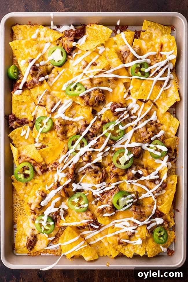 Pulled pork nachos drizzled with sour cream and sprinkled with jalapeno slices.