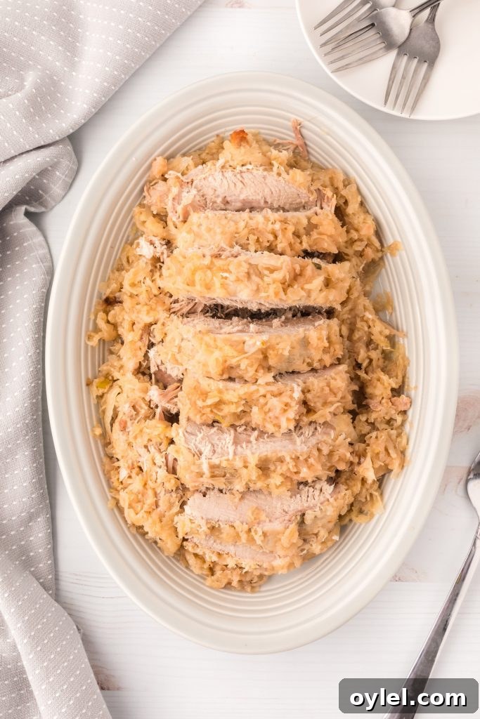 Sliced pork roast on a platter with sauerkraut.