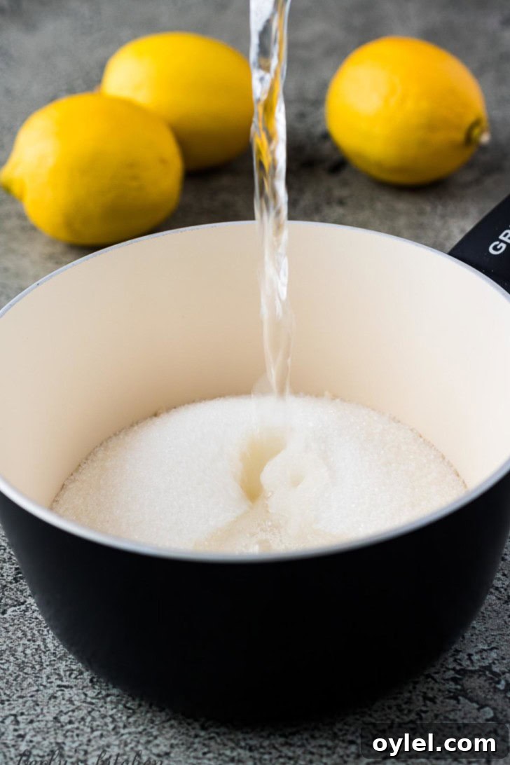 A cup of water pouring into a saucepan with sugar.