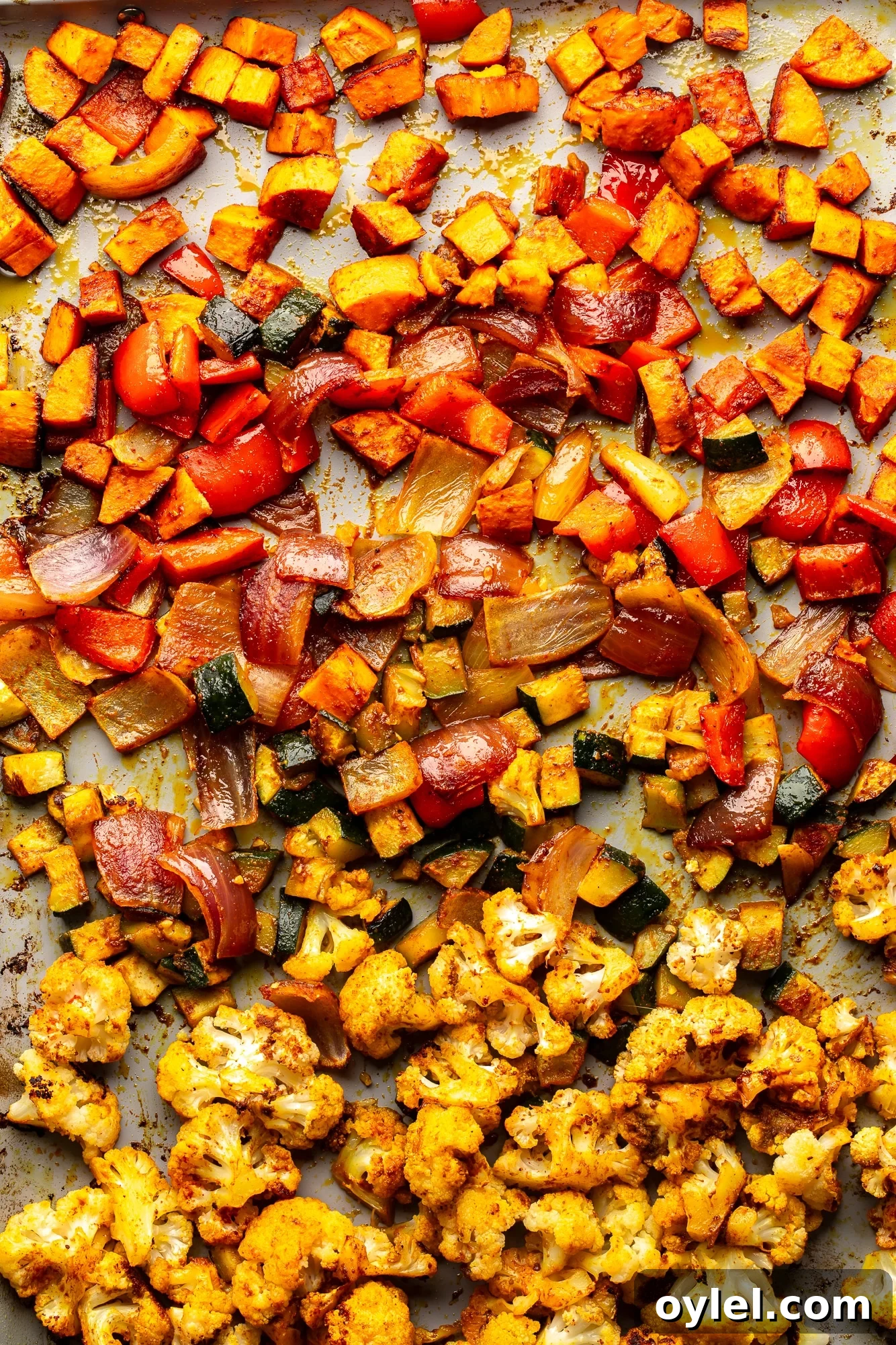 Overhead view of a medley of roasted vegetables on a sheet pan.