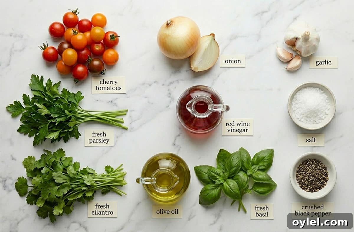 Ingredients for recipe on white marble background- fresh herbs, salt, pepper, onion, garlic, olive oil, cherry tomatoes, red wine vinegar.
