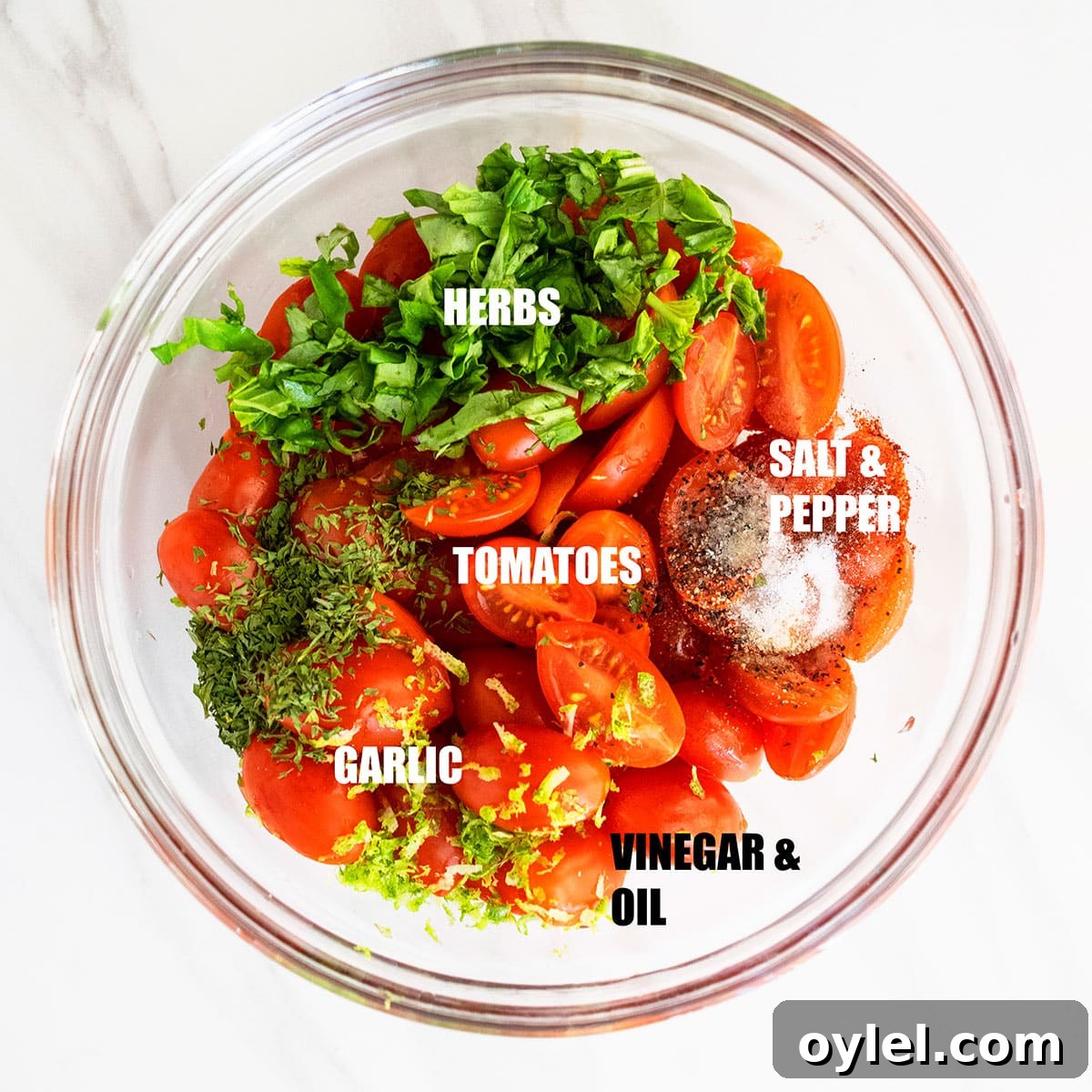 Ingredients in a glass bowl on white marble background ready to be tossed.