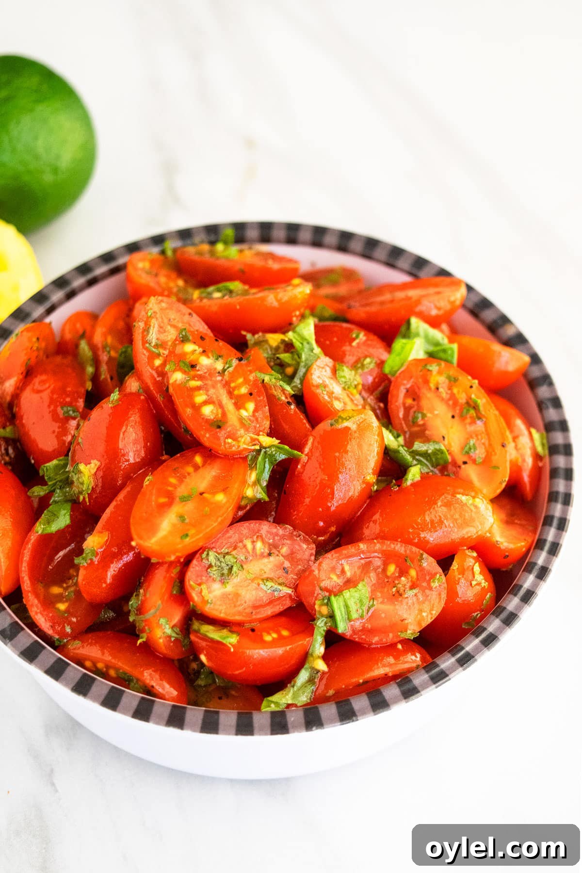Cherry tomatoes and onions with herbs and spices in black and white bowl.