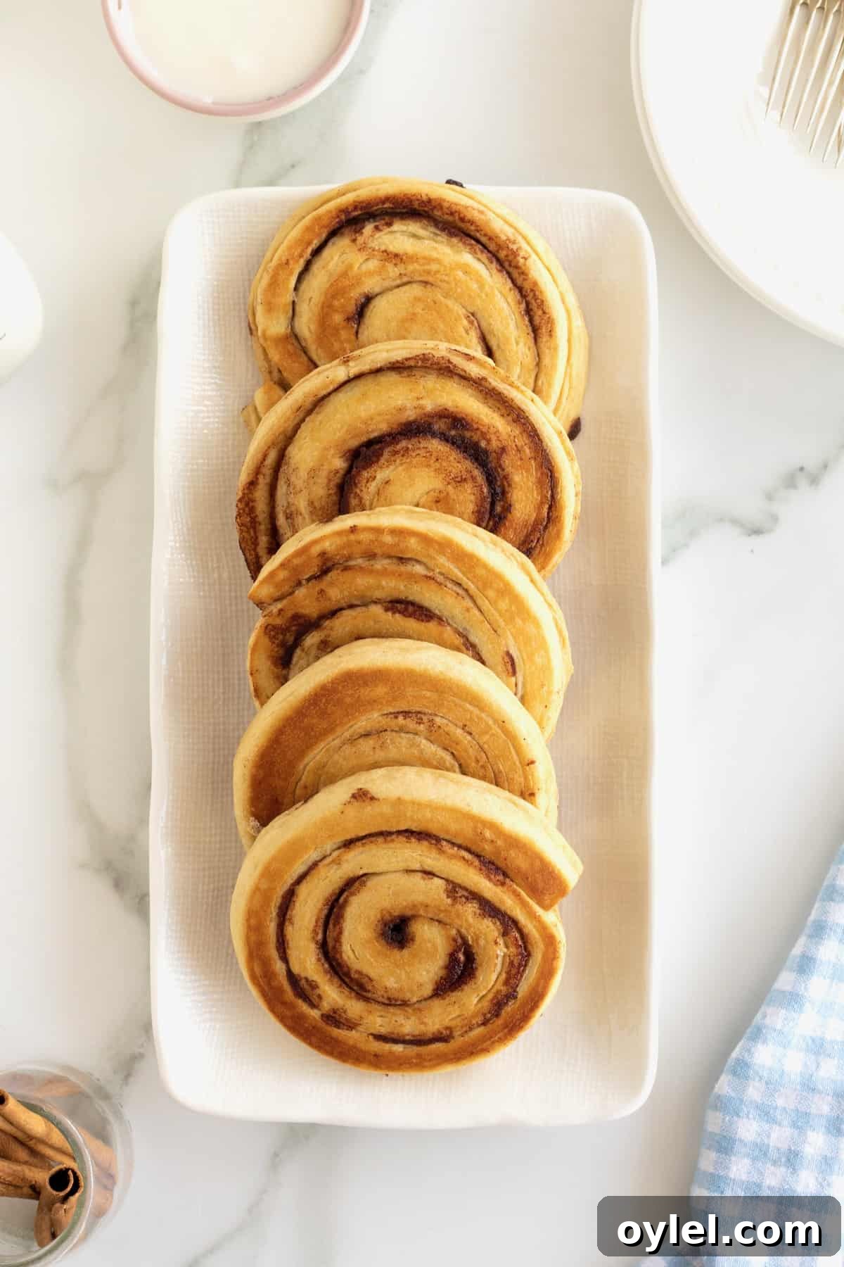 Cinnamon Roll Pancakes Recipe with Cream Cheese Glaze 7 Five cinnamon roll pancakes on a rectangular white serving tray.