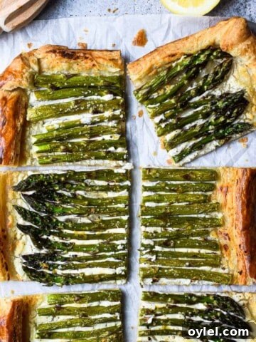 Overhead of asparagus and whipped goat cheese puff pastry tart cut into six pieces with a lemon to the side