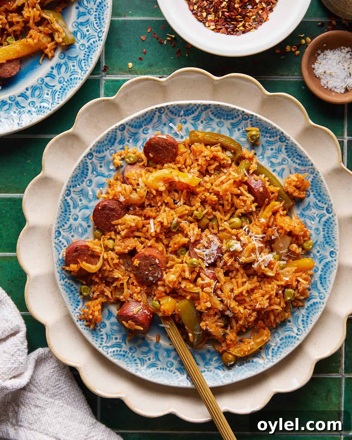 One-Pot Cajun Chicken Sausage and Rice 2 Overhead image of chicken sausage and rice with parmesan topping on white plate with gold fork.