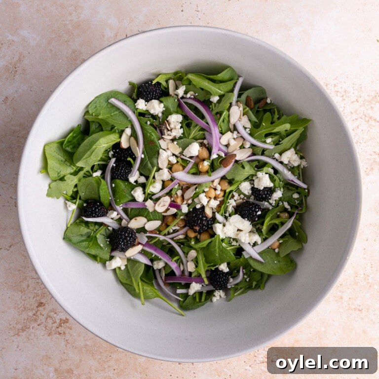 All ingredients for Spinach Arugula Salad in a large mixing bowl