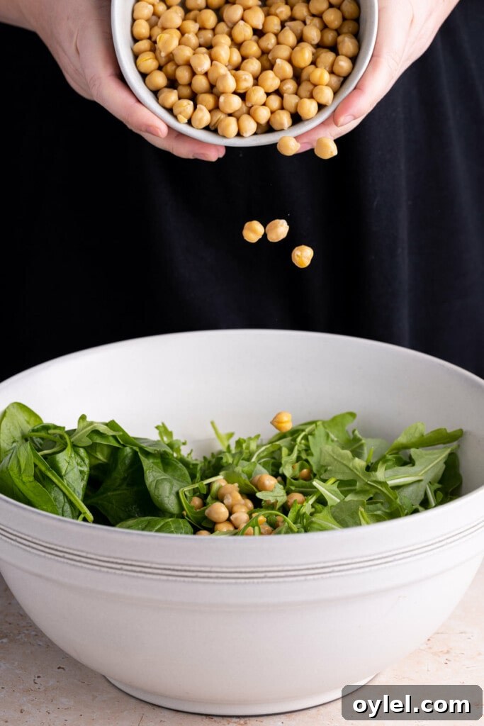 Adding chickpeas to Spinach Arugula Salad.
