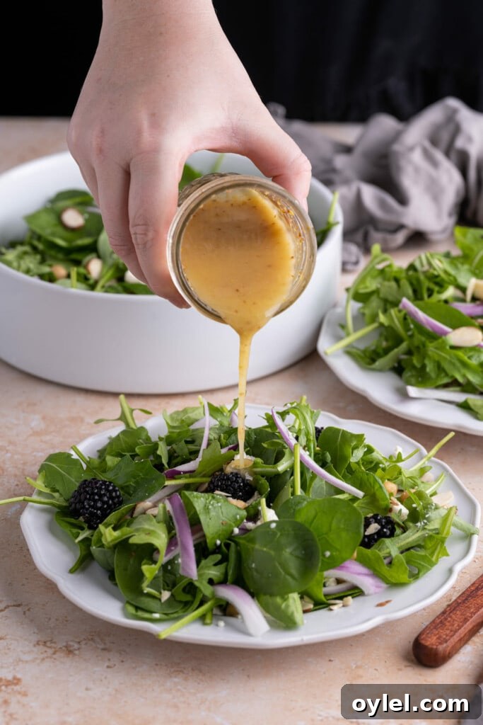 Adding Honey Dijon Vinaigrette to salad just before serving.