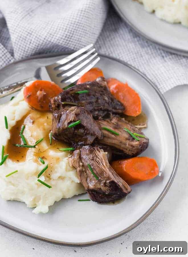 Juicy Instant Pot Beef Roast with Garlic and Herbs 5 Image of Instant Pot Pot Roast on a plate with carrots, mashed potatoes, gravy and a fork.
