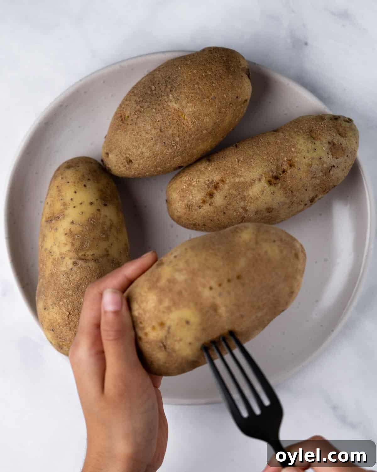Crispy Air Fryer Potato Skins with Cheese and Bacon 4 Poking holes into potato with fork.