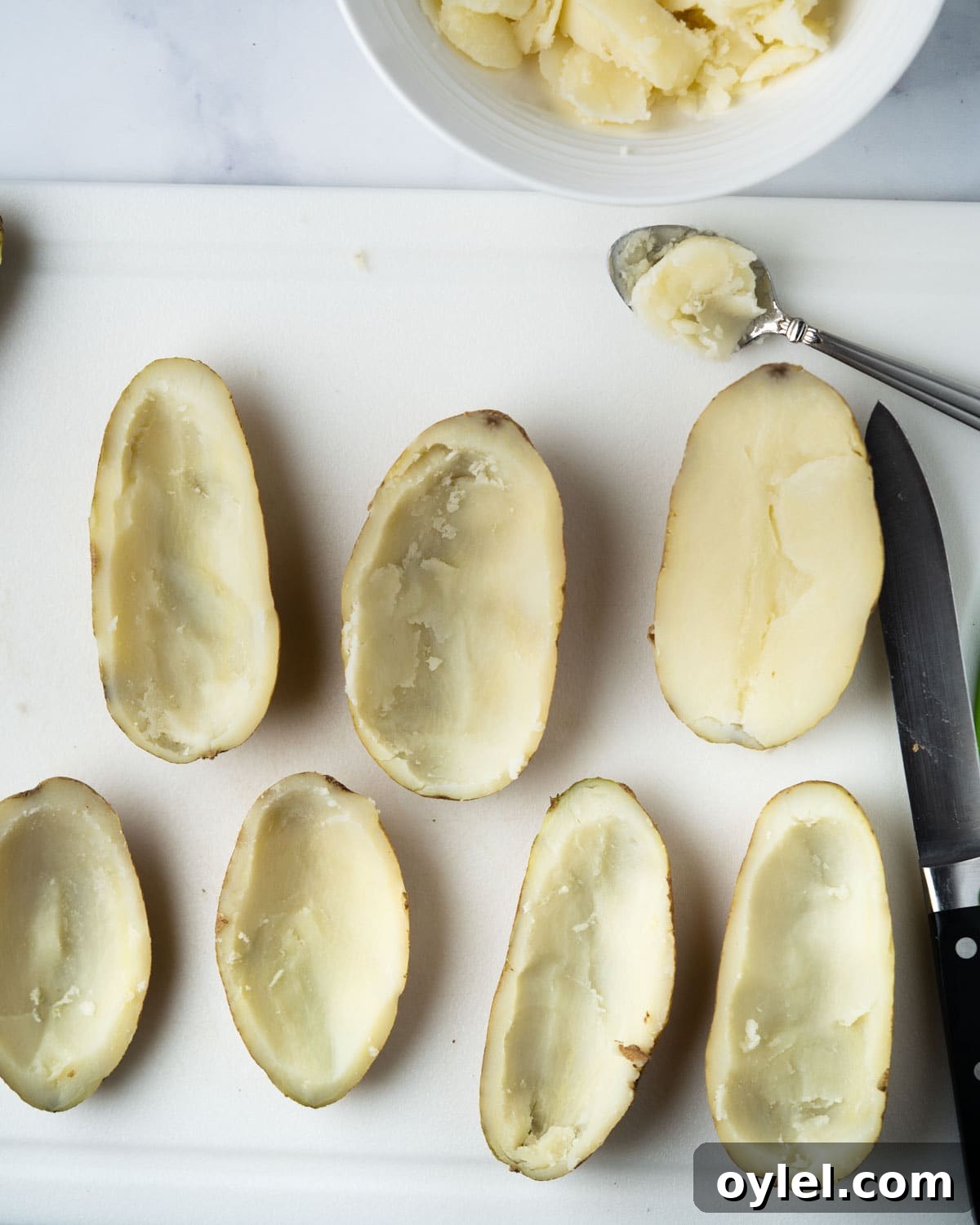 Crispy Air Fryer Potato Skins with Cheese and Bacon 5 scooping out middle of potato with spoon.