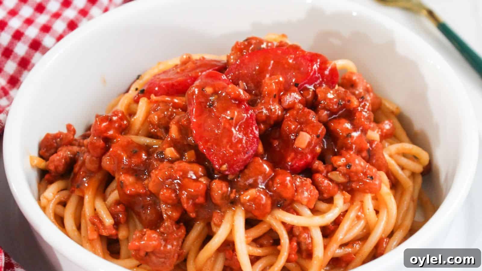 13 Asian Recipes You Won't Believe Are This Simple 14 A bowl of spaghetti topped with a rich meat sauce placed on a red and white checkered tablecloth.