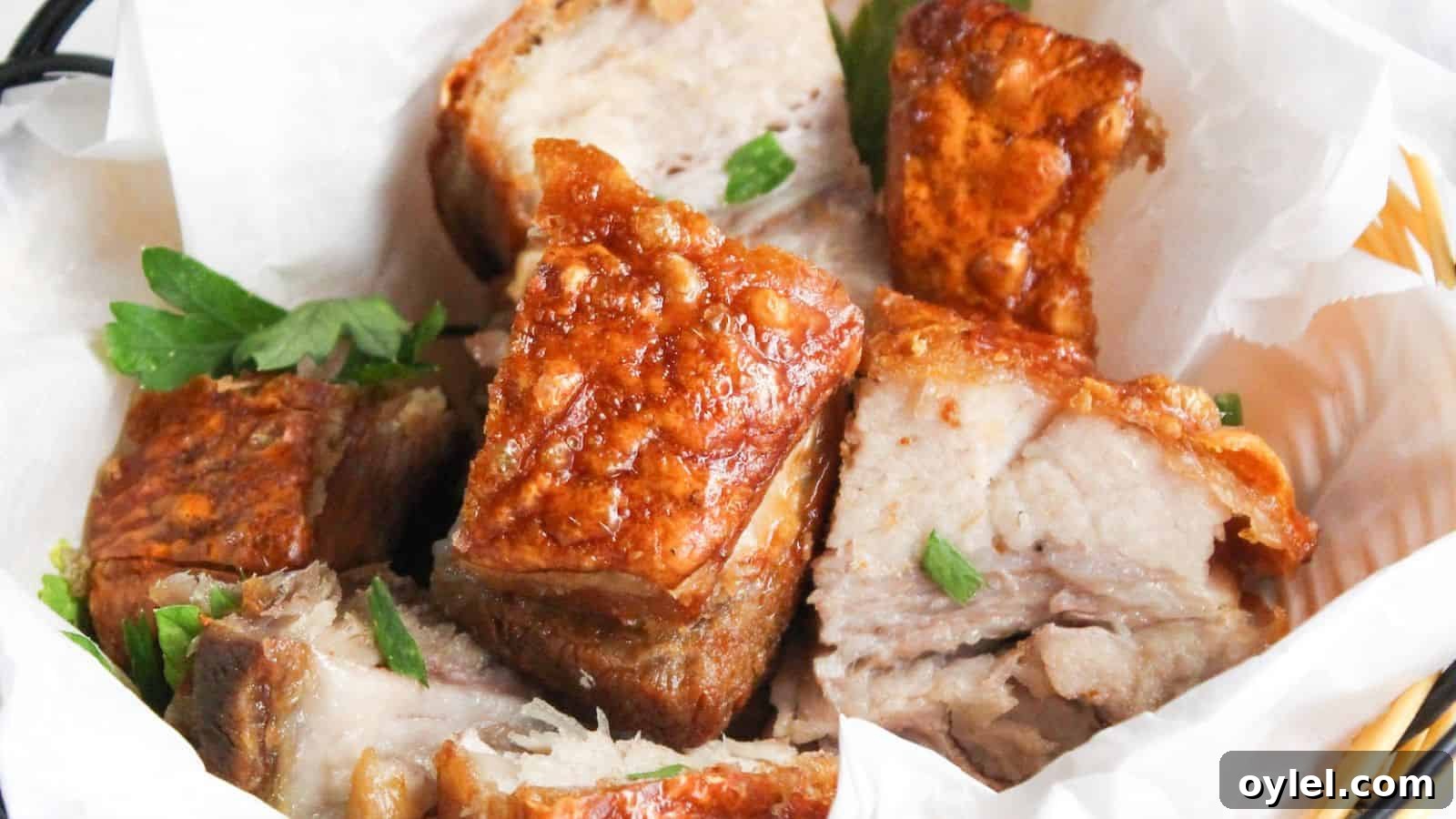 13 Asian Recipes You Won't Believe Are This Simple 4 A basket of crispy roasted pork belly chunks garnished with parsley, served in a white paper-lined wicker basket.