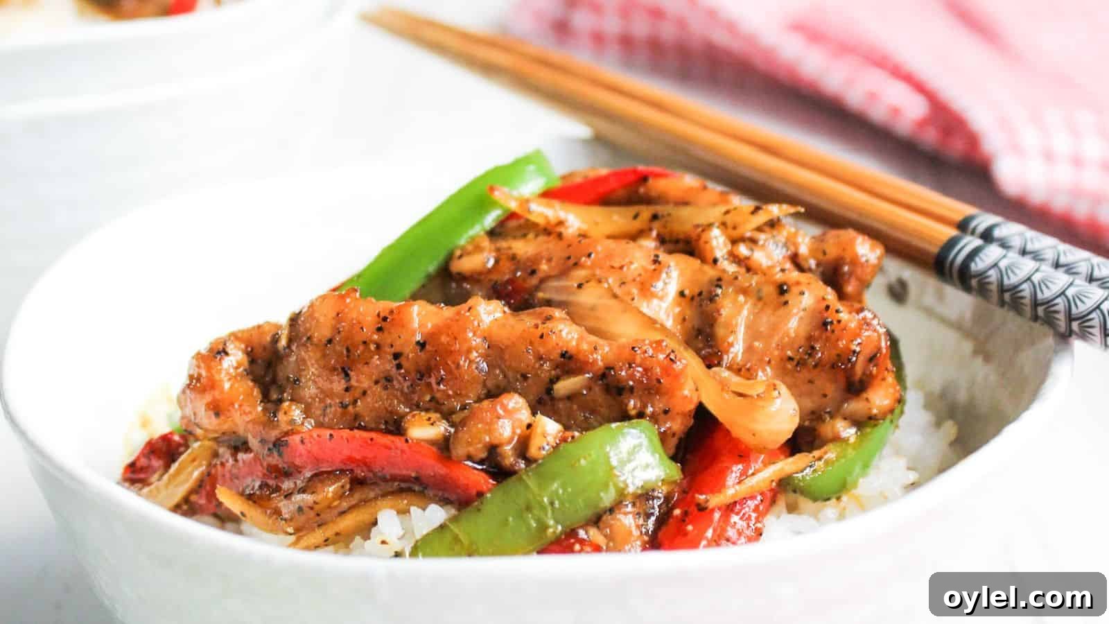 13 Asian Recipes You Won't Believe Are This Simple 6 A bowl of chicken stir-fry with vegetables served over rice, accompanied by chopsticks.
