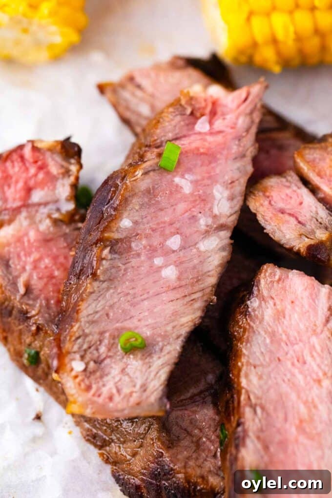 Close shot of slices of juicy Asian style grilled rib-eye steak topped with sea salt and chopped green onions.