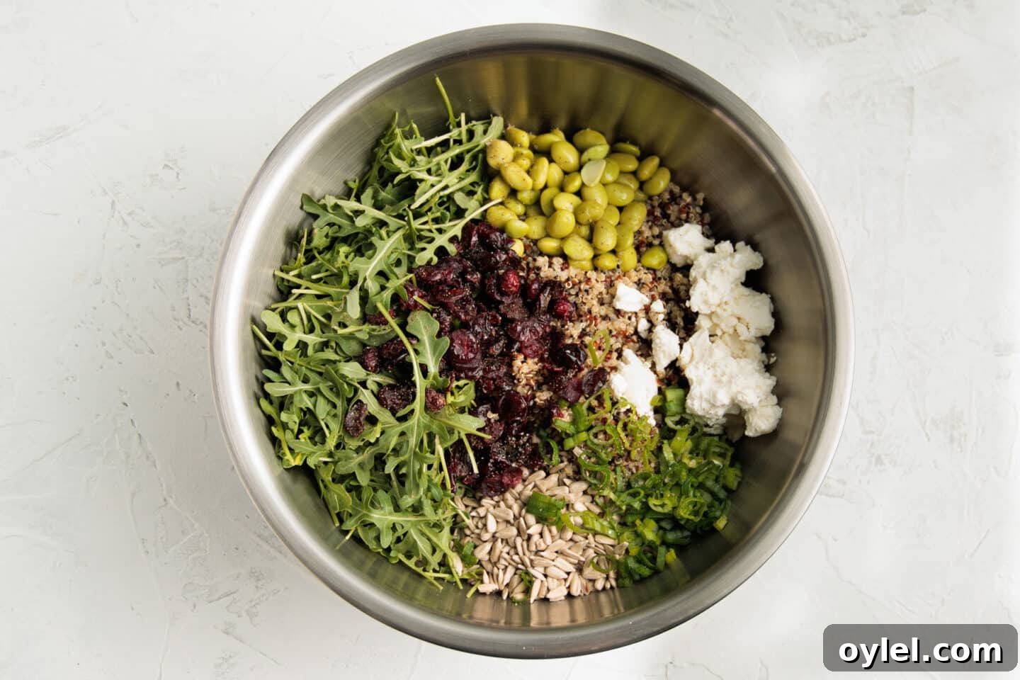 Bowl with all ingredients of quinoa arugula salad before being tossed together.