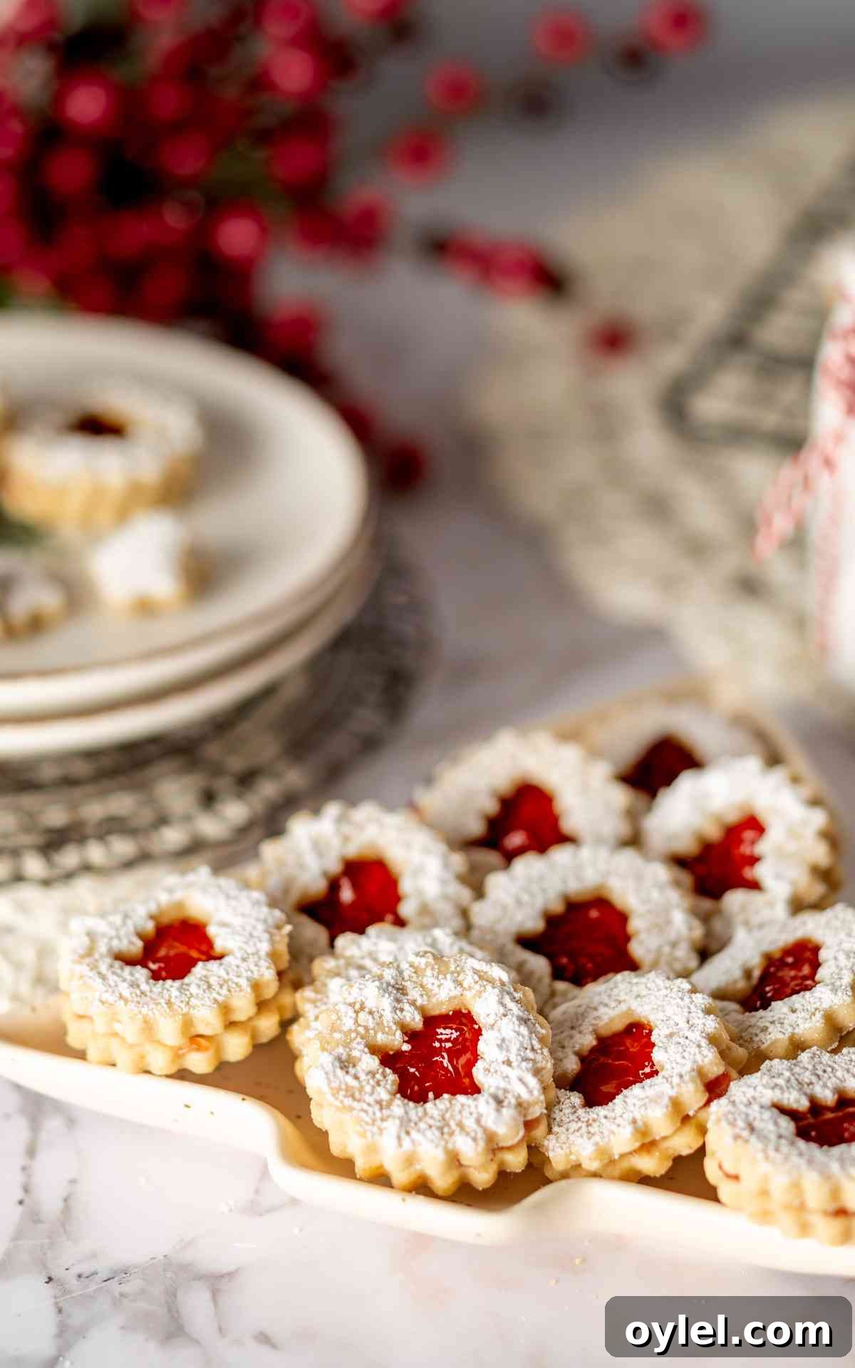 Linzer tarts with raspberry filling on a Christmas tree plate.