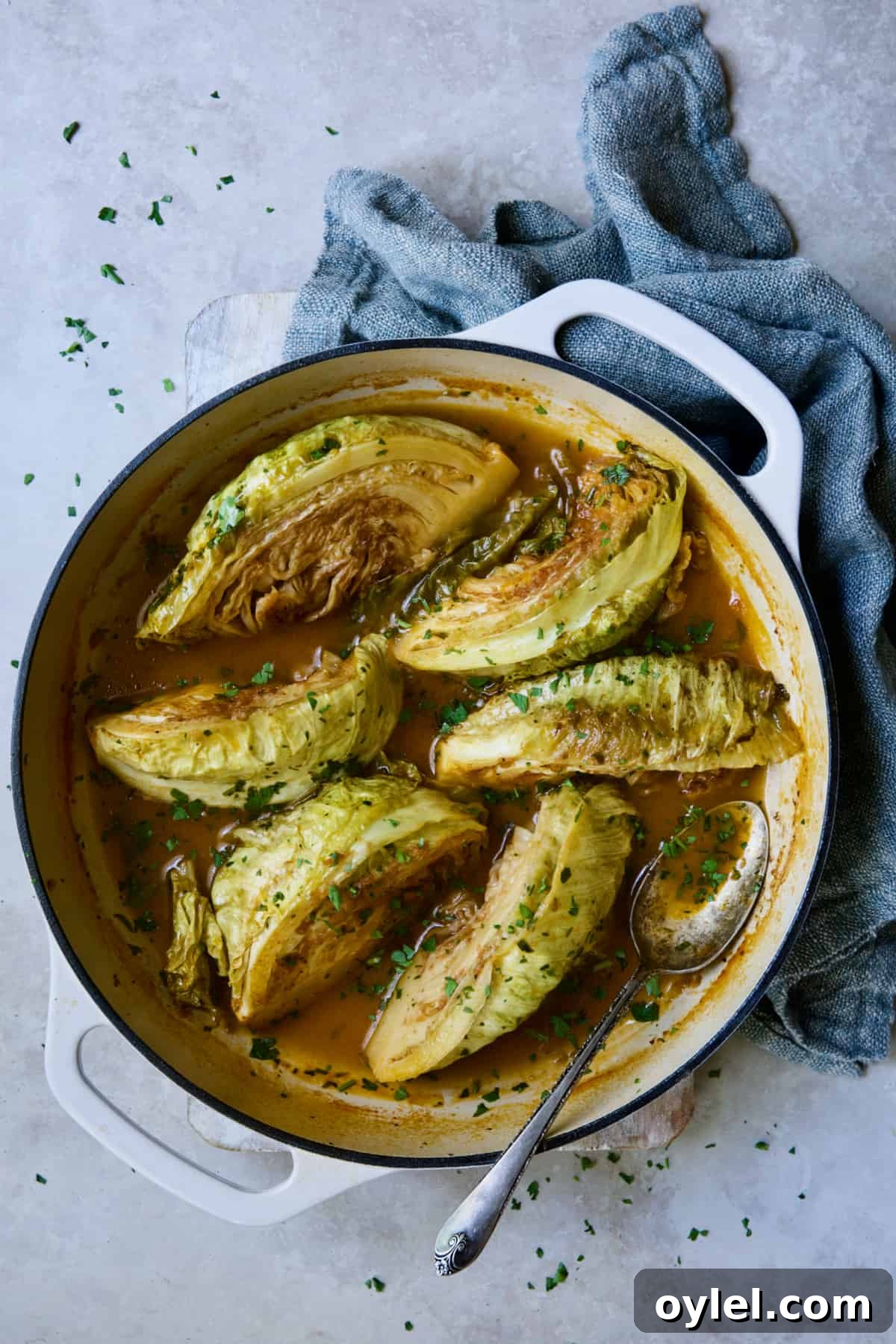 Cider Vinegar Braised Cabbage Wedges in white cast iron skillet garnished with fresh parsley.