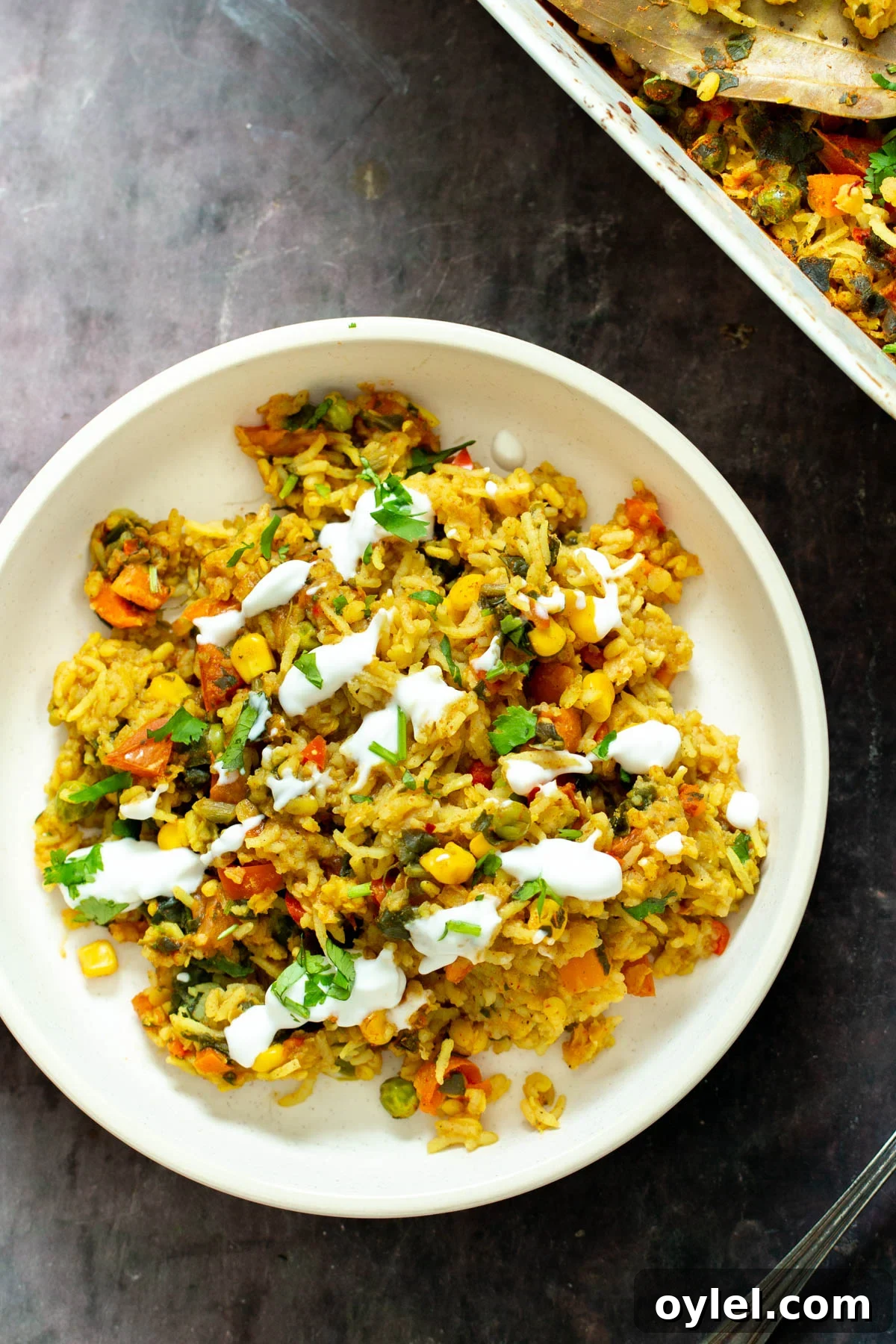 a plate of vegan baked kitchari lentil rice casserole served with fresh herbs and yogurt 