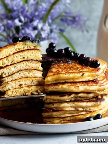 A plate with a stack of sourdough discard pancakes with a slice of them taken out.