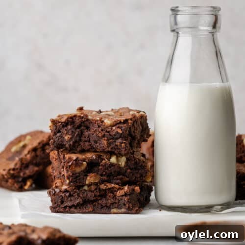 A stack of gluten free brownies next to a jug of milk.